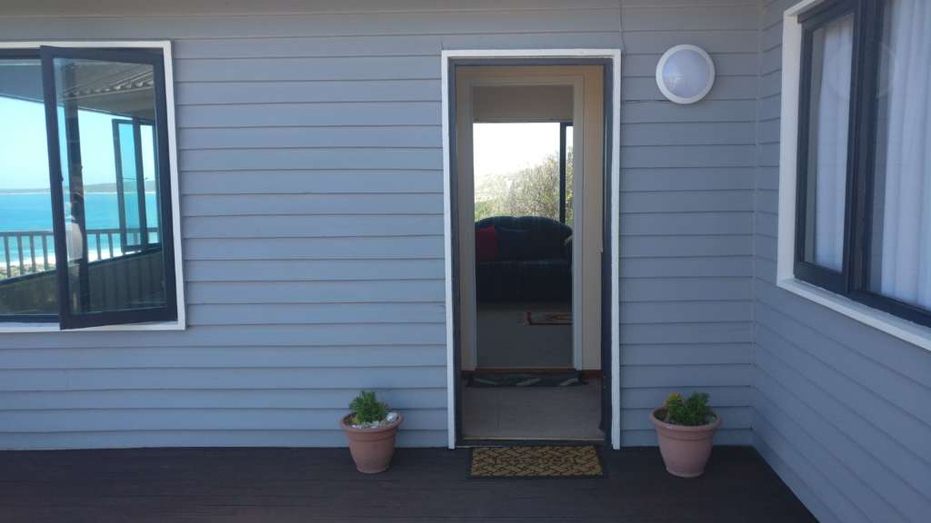 Porte d'entrée de la terrasse à la maison principale au Fonteintjies. Des plantes en pot se tiennent de chaque côté de la porte et il y a un tapis de bienvenue.