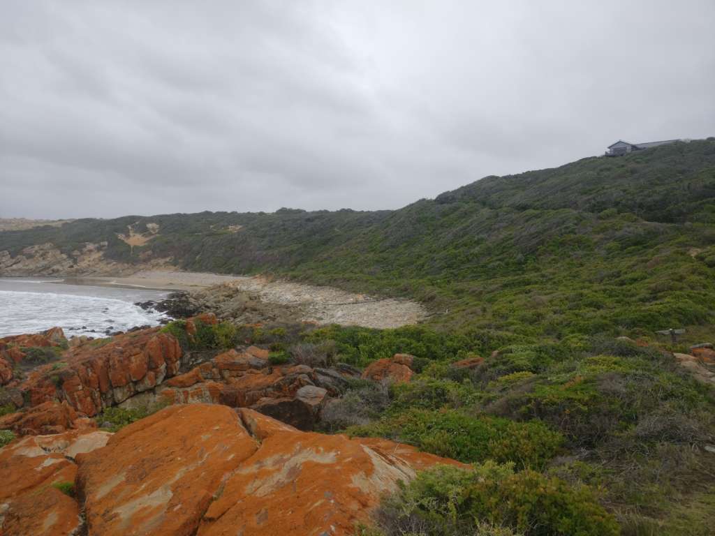 'n Rotsagtige seekus. 'n Sanderige bek is in die verte sigbaar. Die huis by Fonteintjies is aan die regterkant op die horison.