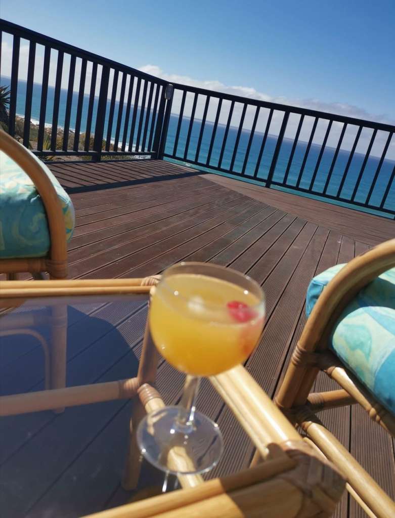 Ein Mimosengetränk auf einem kleinen Tisch auf dem Deck. Zwei bequeme Stühle haben Meerblick.